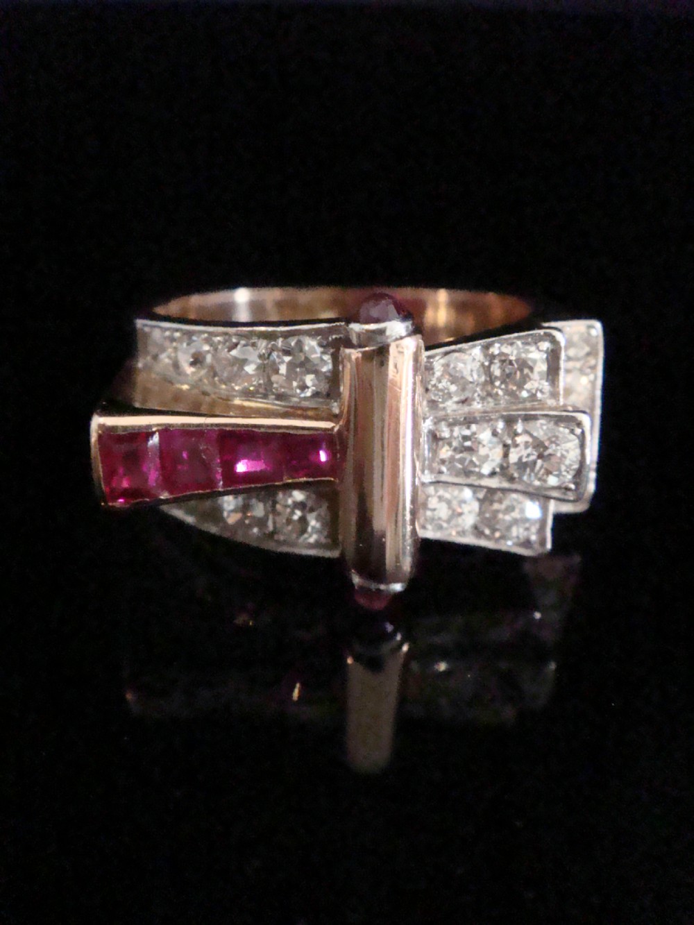 An 18ct gold Retro Modern tank ring featuring geometric diamond shoulders and a channel of calibre-cut red rubies. View IX