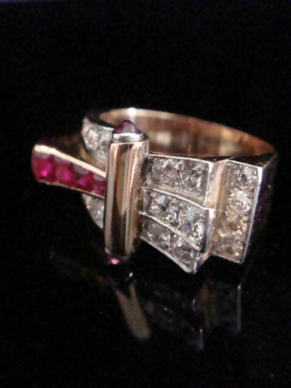 An 18ct gold Retro Modern tank ring featuring geometric diamond shoulders and a channel of calibre-cut red rubies. View XI