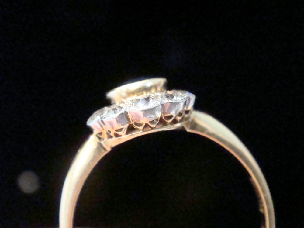 An Edwardian 18ct gold cluster ring featuring a central oval blue sapphire surrounded by a scalloped halo of small diamonds. View V