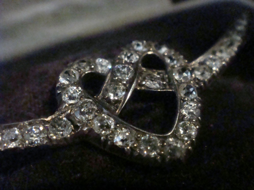 An Edwardian heart-shaped brooch set with diamonds and flanked by curved winged extensions, resting in a velvet fitted box. View II