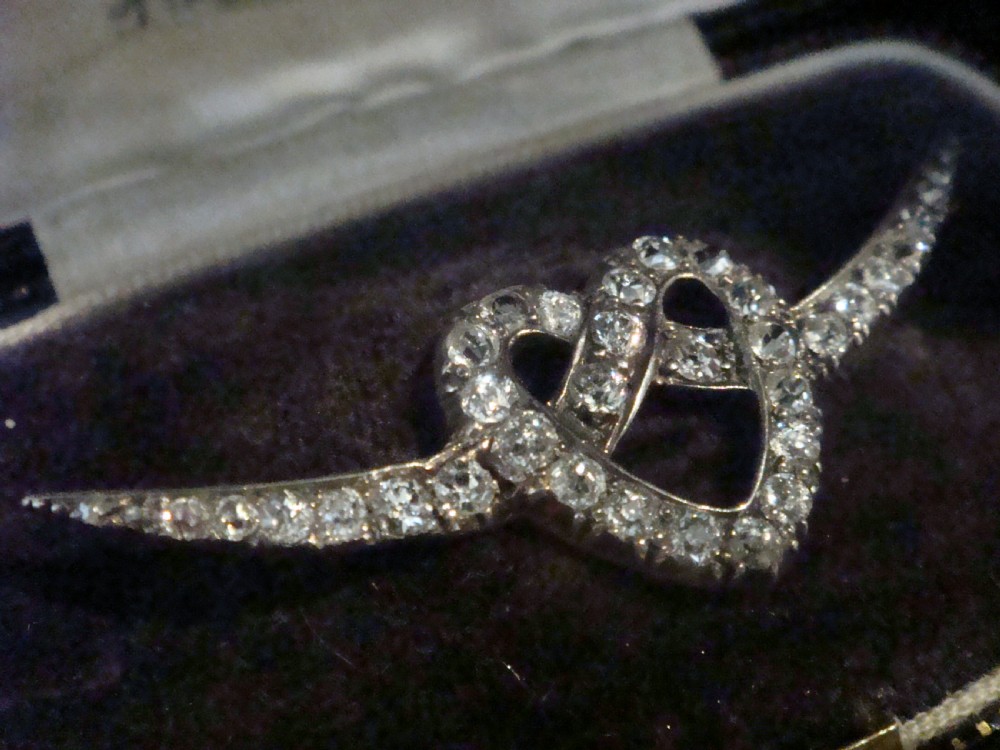 An Edwardian heart-shaped brooch set with diamonds and flanked by curved winged extensions, resting in a velvet fitted box. View III