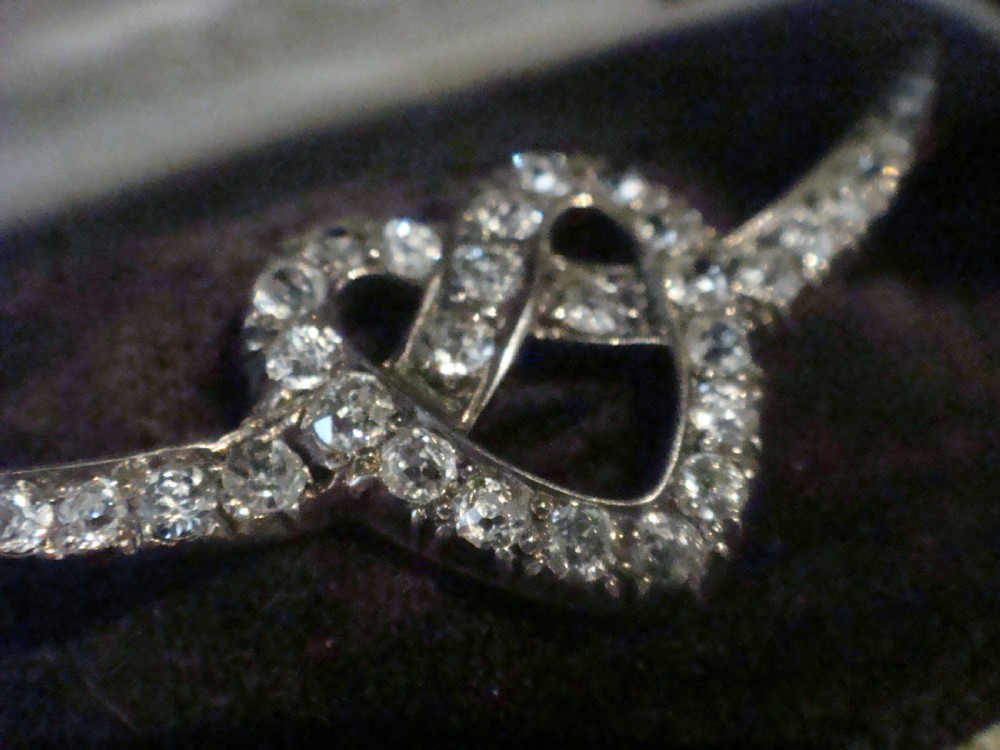 An Edwardian heart-shaped brooch set with diamonds and flanked by curved winged extensions, resting in a velvet fitted box. View IV