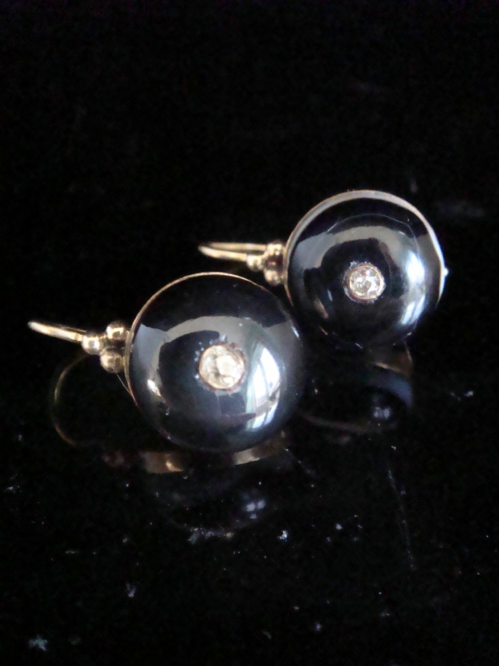 A pair of spherical black agate drop earrings mounted in 9ct yellow gold with a single small diamond set in the centre of each stone.