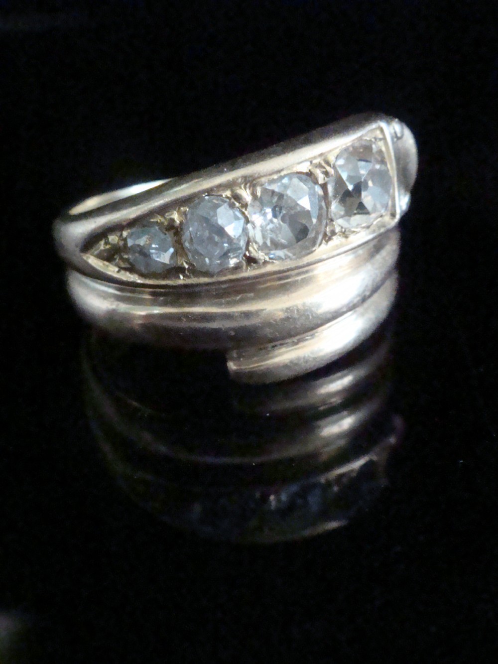 An 18ct gold Victorian coiled serpent ring set with a row of graduated old cut diamonds across the head.