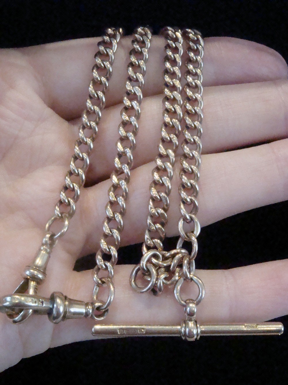 An Edwardian 9ct rose gold curb-link Albert chain featuring double dog clips and a central T-bar.