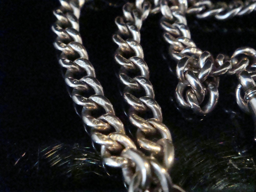 An Edwardian 9ct rose gold curb-link Albert chain featuring double dog clips and a central T-bar. View II