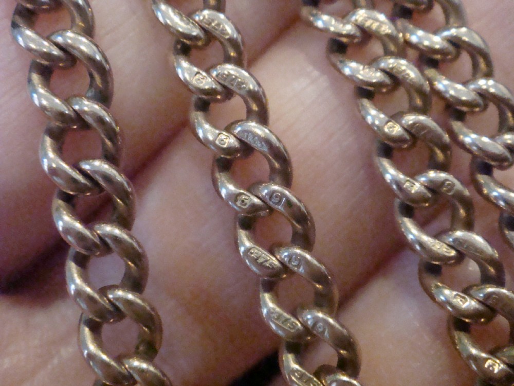An Edwardian 9ct rose gold curb-link Albert chain featuring double dog clips and a central T-bar. View VII