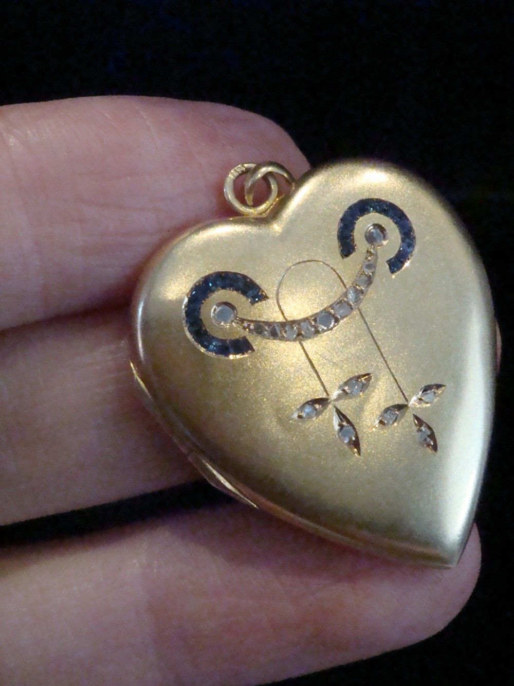 An 18ct yellow gold heart-shaped locket embellished with diamonds and sapphires in a garland pattern. View II