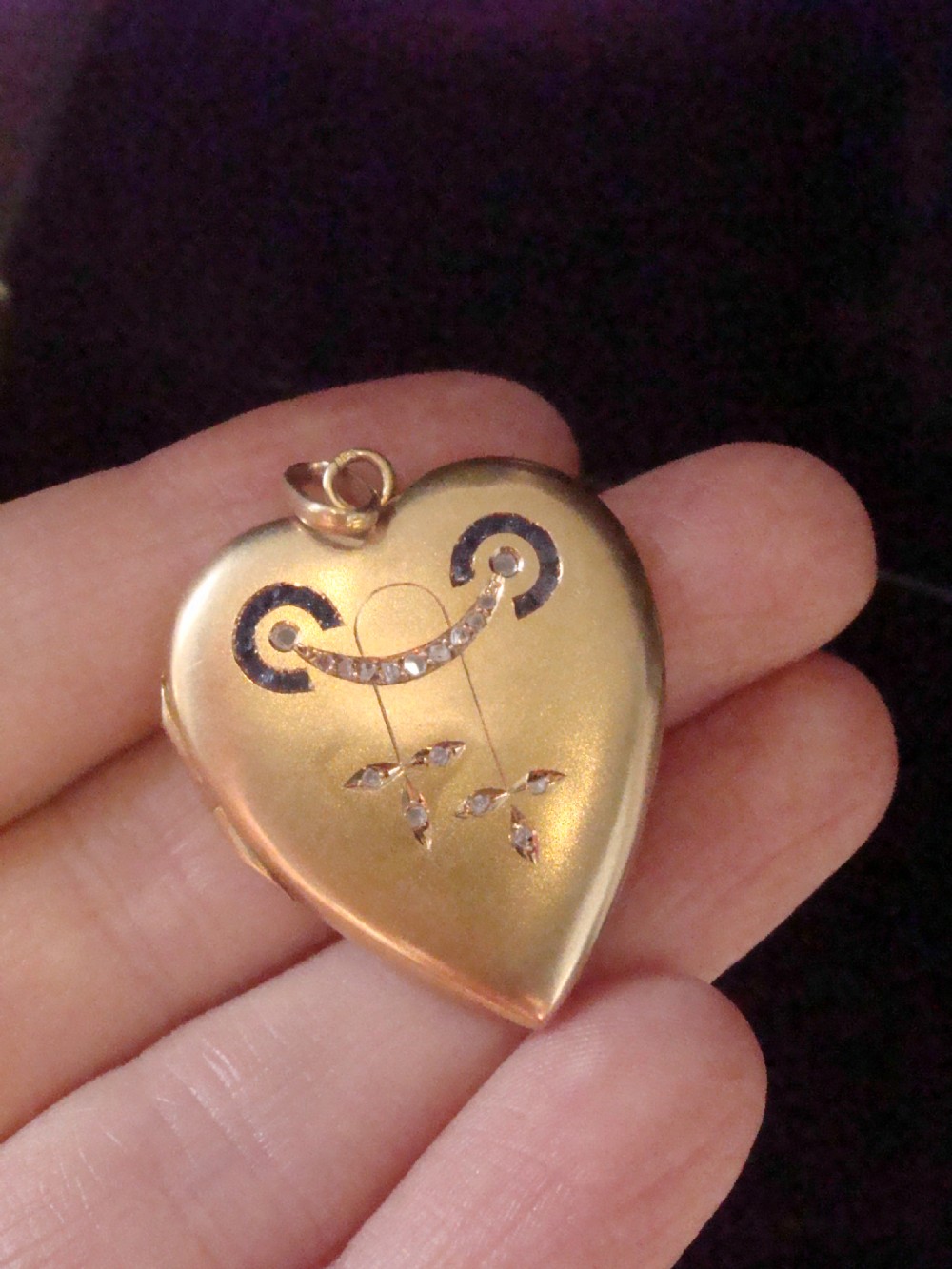 An 18ct yellow gold heart-shaped locket embellished with diamonds and sapphires in a garland pattern. View III