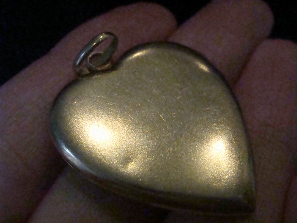 An 18ct yellow gold heart-shaped locket embellished with diamonds and sapphires in a garland pattern. View V