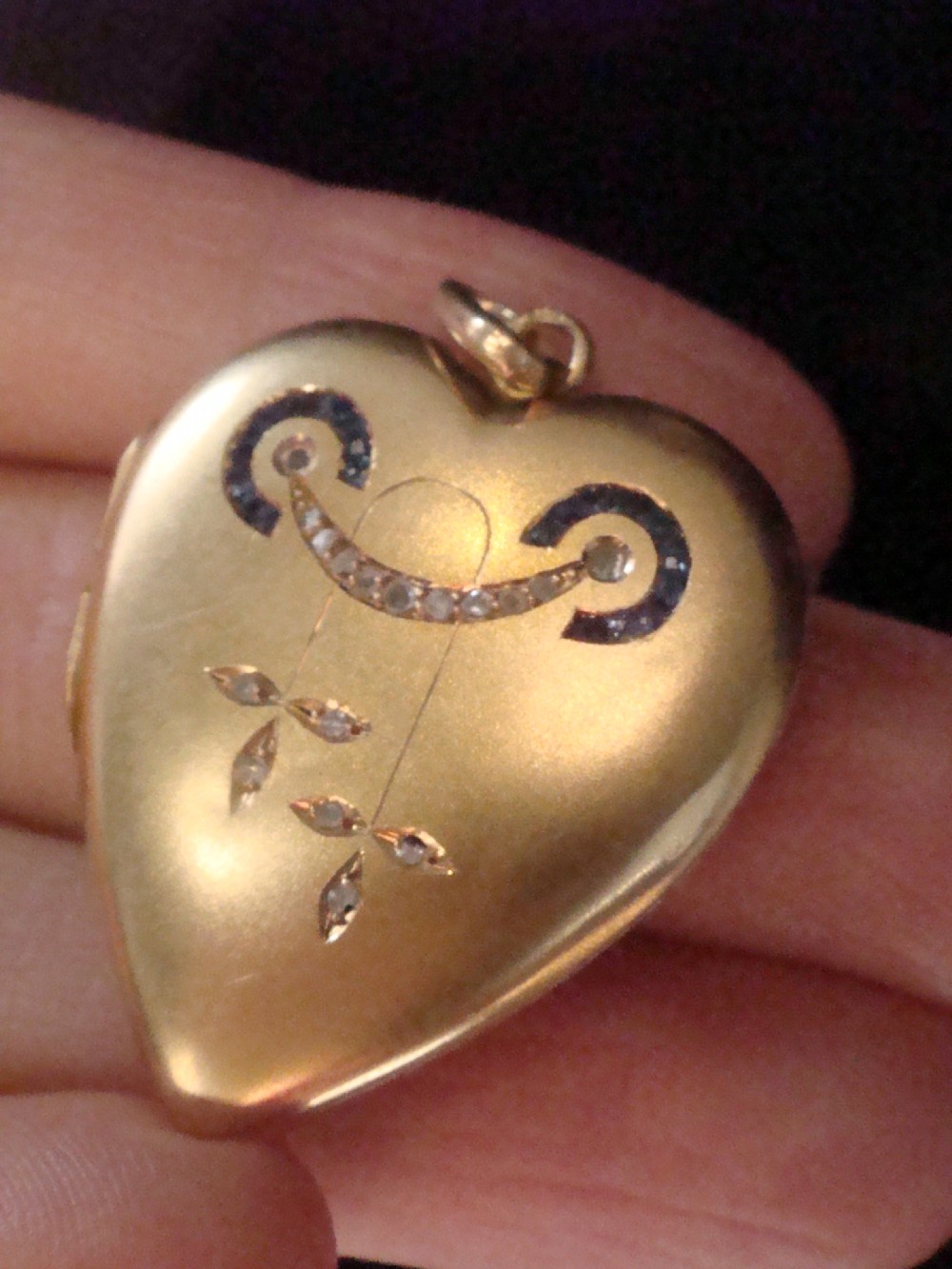 An 18ct yellow gold heart-shaped locket embellished with diamonds and sapphires in a garland pattern. View VII