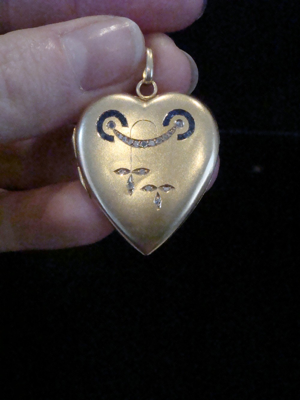 An 18ct yellow gold heart-shaped locket embellished with diamonds and sapphires in a garland pattern. View VIII