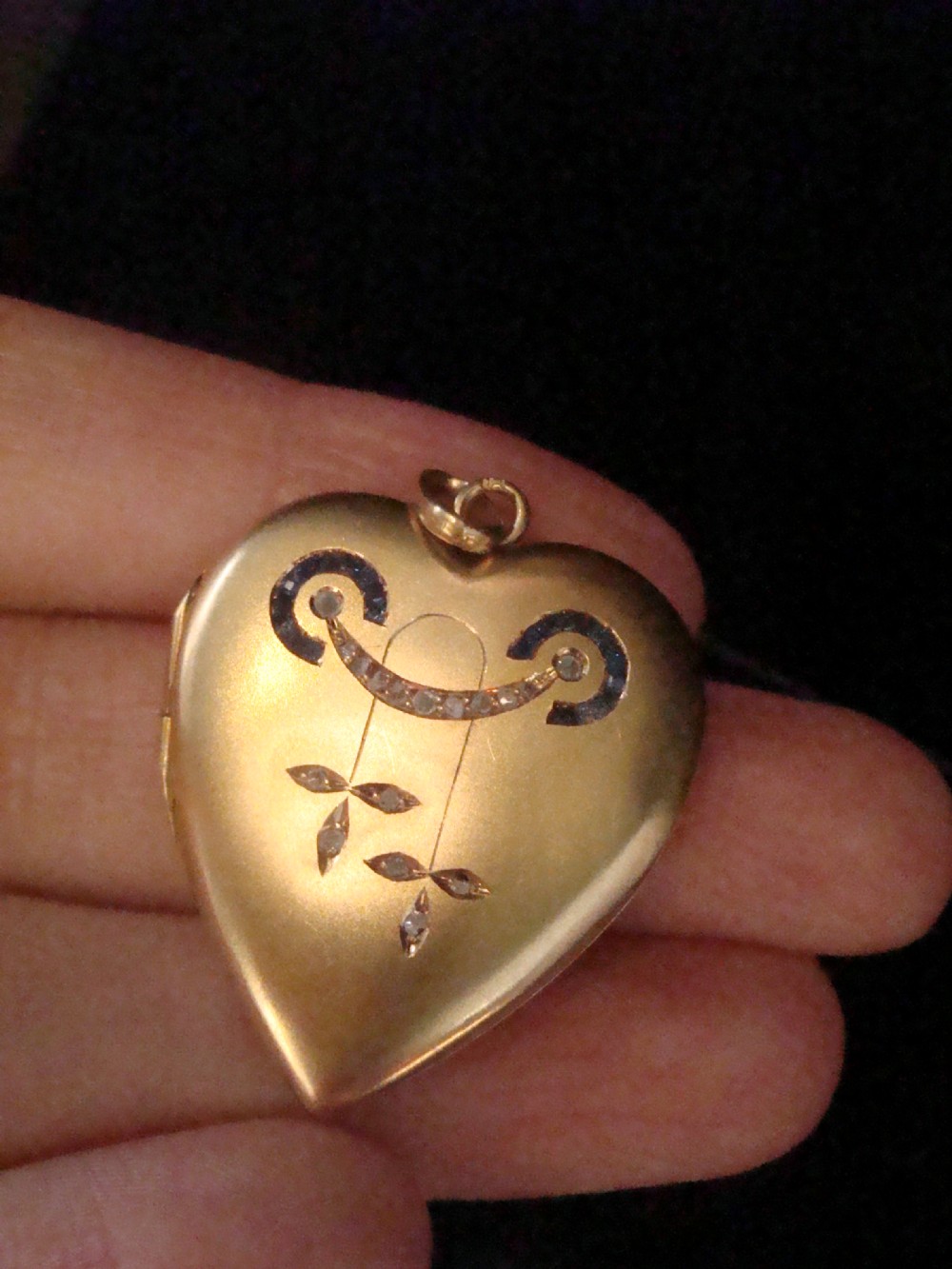 An 18ct yellow gold heart-shaped locket embellished with diamonds and sapphires in a garland pattern. View IX