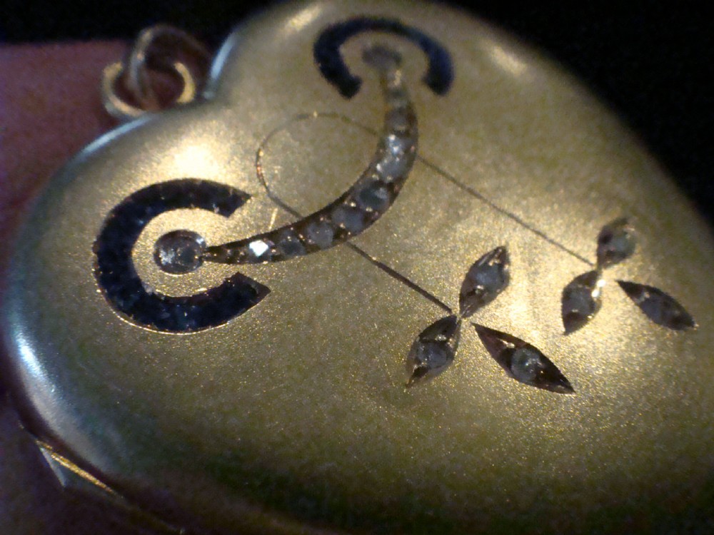 An 18ct yellow gold heart-shaped locket embellished with diamonds and sapphires in a garland pattern. View XI