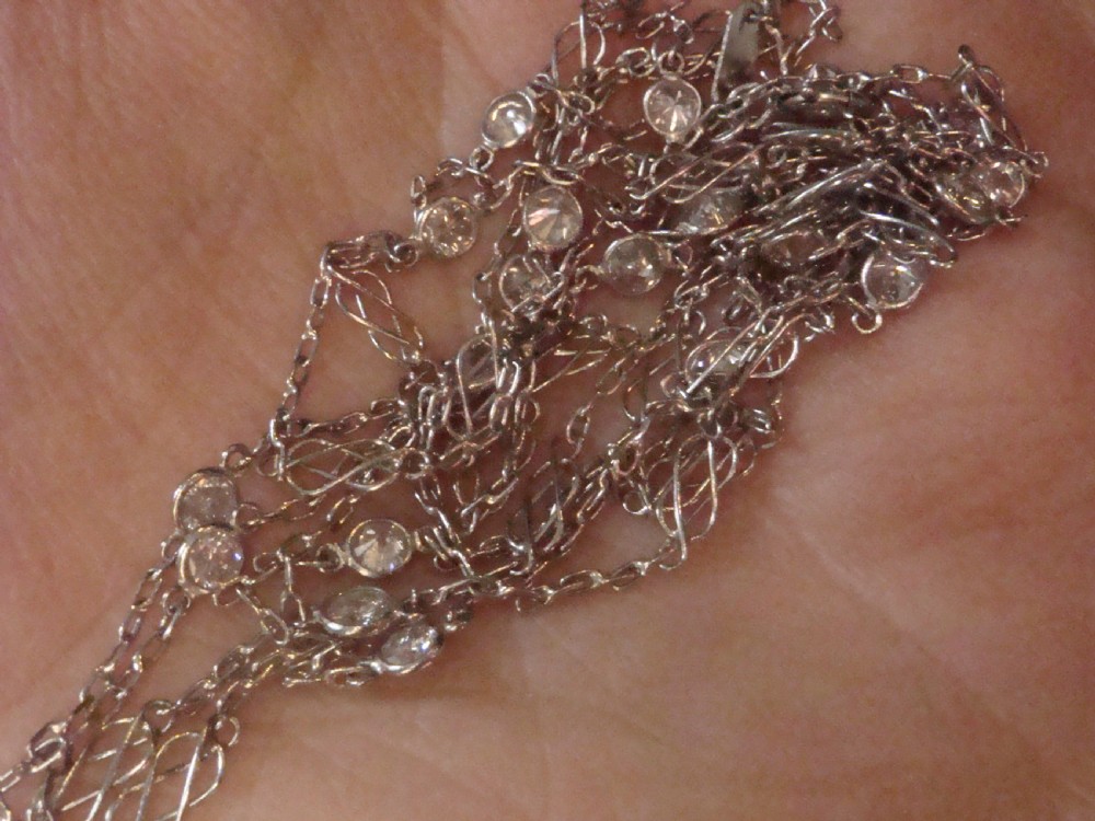 An Edwardian 18ct white gold longuard chain featuring spectacle-set round diamonds interspersed with delicate open wirework links. View III