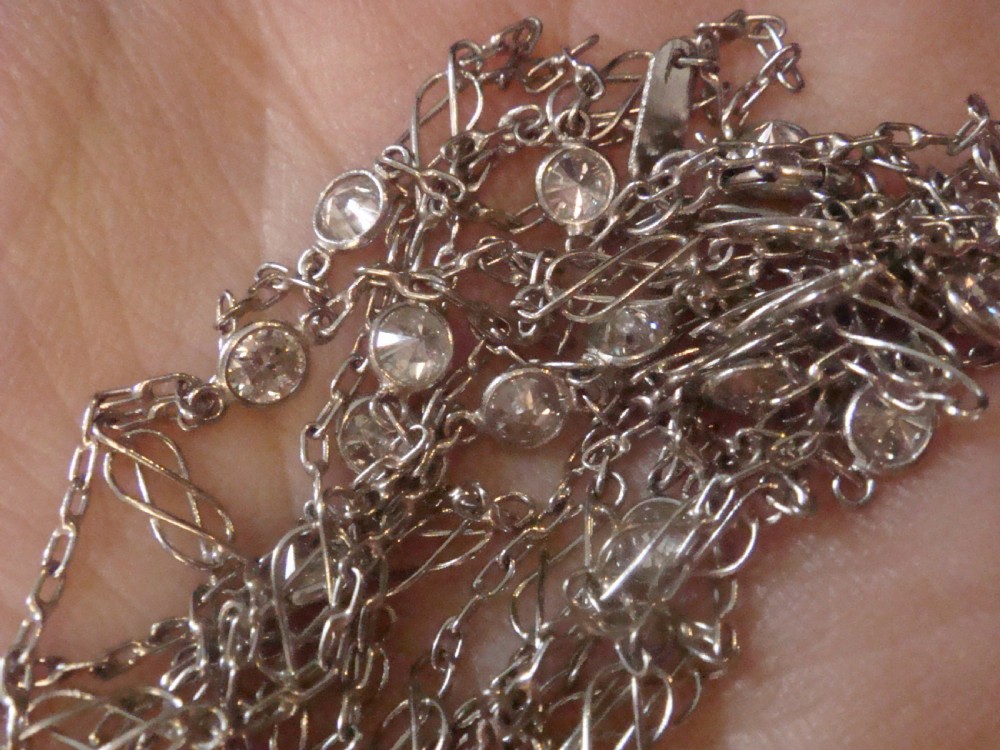 An Edwardian 18ct white gold longuard chain featuring spectacle-set round diamonds interspersed with delicate open wirework links. View IV