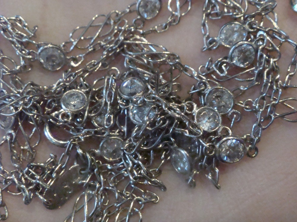 An Edwardian 18ct white gold longuard chain featuring spectacle-set round diamonds interspersed with delicate open wirework links. View IX