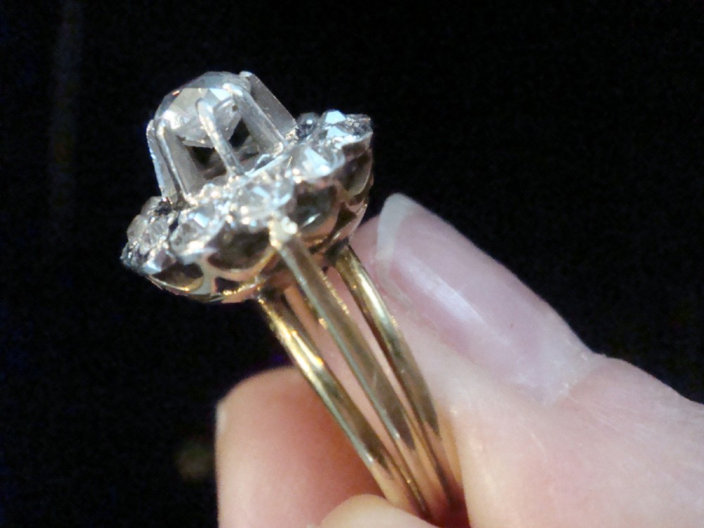 An Edwardian 18ct yellow gold cluster ring set with a central old-cut diamond surrounded by a floral halo of smaller old-cut diamonds. View IV
