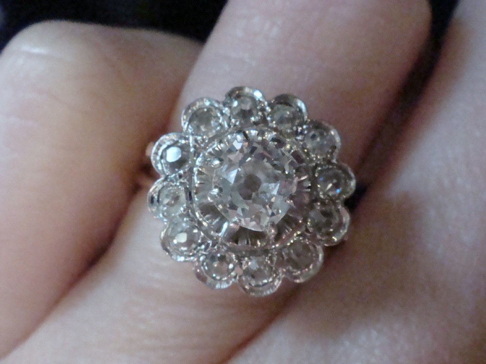 An Edwardian 18ct yellow gold cluster ring set with a central old-cut diamond surrounded by a floral halo of smaller old-cut diamonds. View V