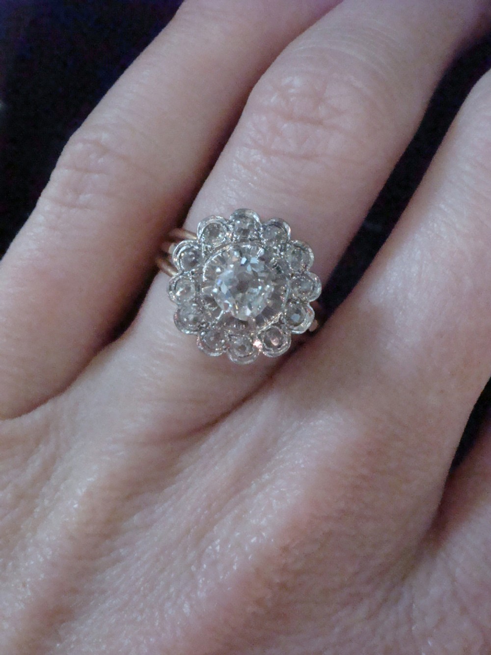 An Edwardian 18ct yellow gold cluster ring set with a central old-cut diamond surrounded by a floral halo of smaller old-cut diamonds. View VI