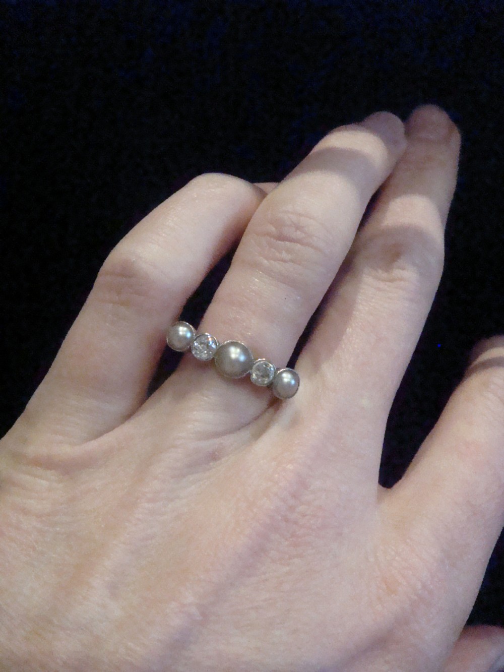 An Edwardian 18ct gold five-stone ring featuring three graduated pearls interspersed with two round diamonds in bezel settings. View II