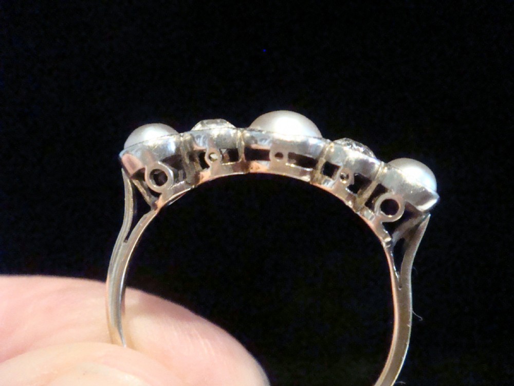 An Edwardian 18ct gold five-stone ring featuring three graduated pearls interspersed with two round diamonds in bezel settings. View III