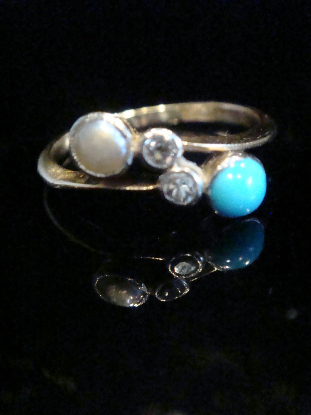 An Edwardian 18ct yellow gold crossover ring set with a turquoise cabochon, a pearl, and two accent diamonds.