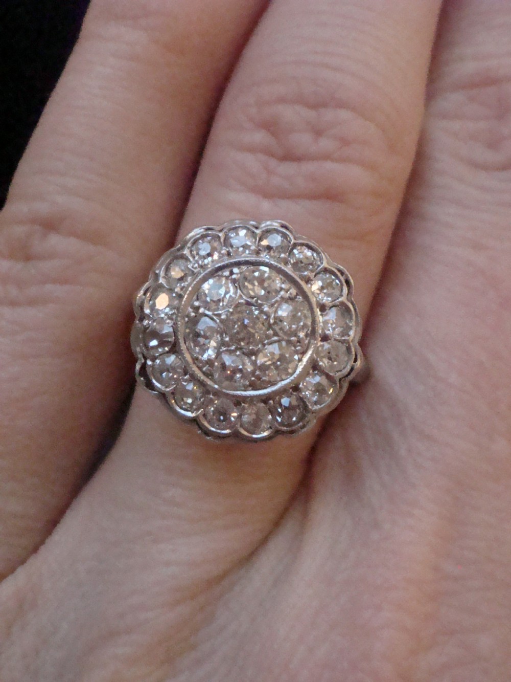 A circular 18ct white gold Edwardian cluster ring set with multiple old cut diamonds featuring a scalloped edge. View III