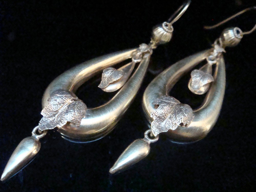 A pair of Victorian 9ct yellow gold drop earrings featuring open teardrop frames embellished with detailed leaf motifs and hanging lower drops.