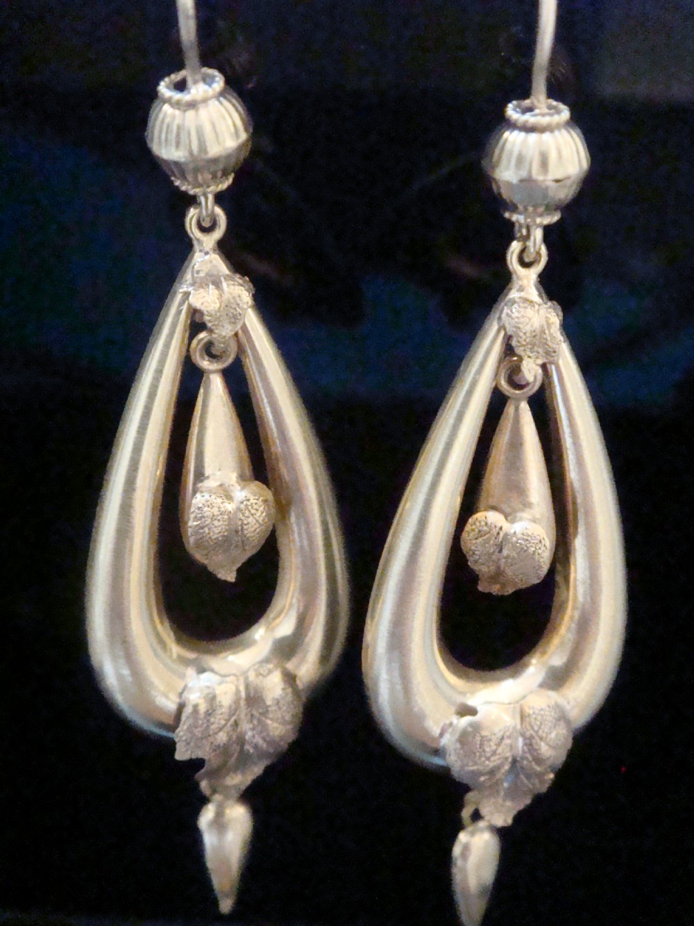 A pair of Victorian 9ct yellow gold drop earrings featuring open teardrop frames embellished with detailed leaf motifs and hanging lower drops. View IV