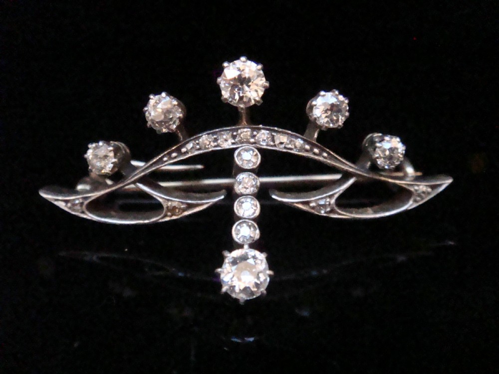 An Edwardian platinum and 18ct gold brooch designed in a tiara shape and set with old cut diamonds.