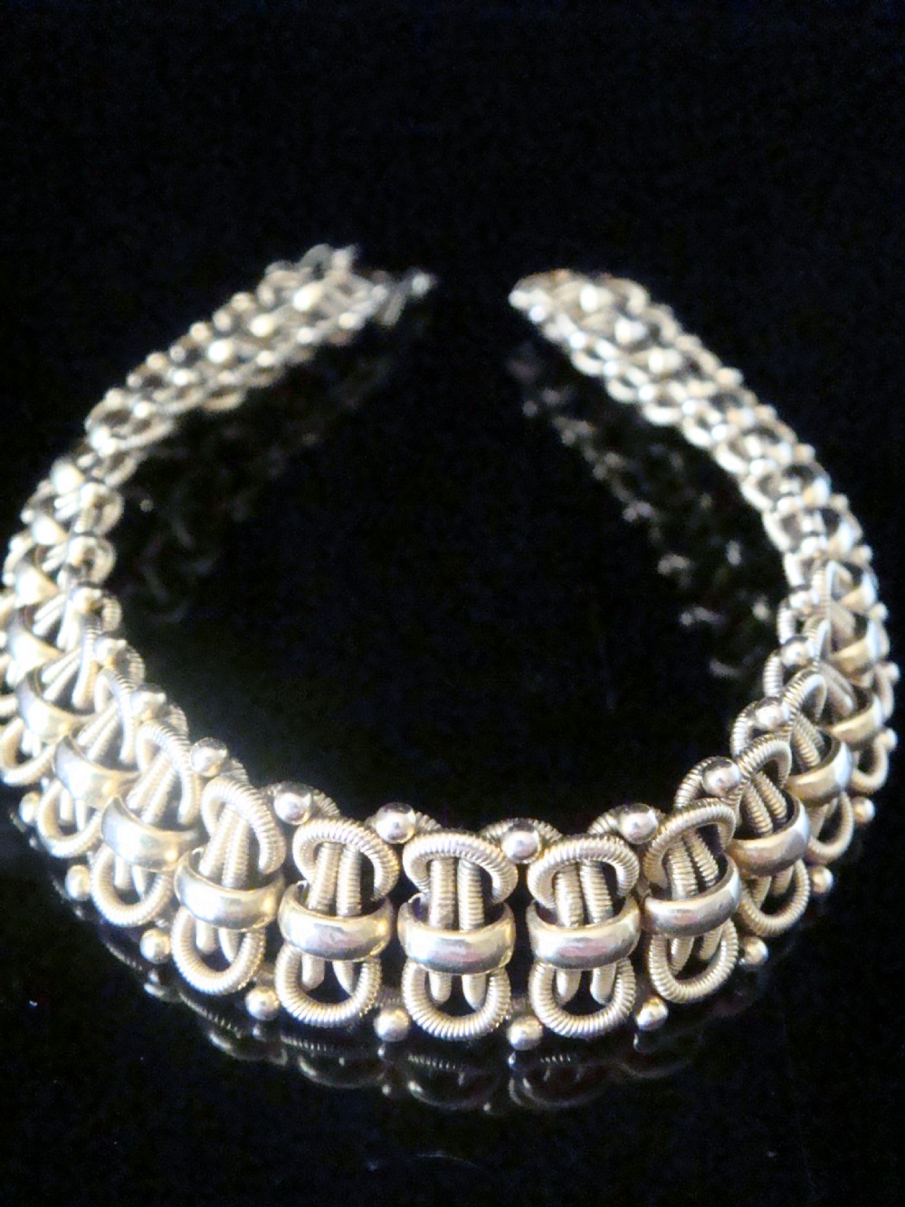 An Edwardian 18ct yellow gold bracelet featuring intricate interlocking wirework links and granulated bead detailing.