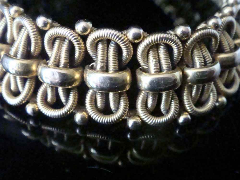 An Edwardian 18ct yellow gold bracelet featuring intricate interlocking wirework links and granulated bead detailing. View III