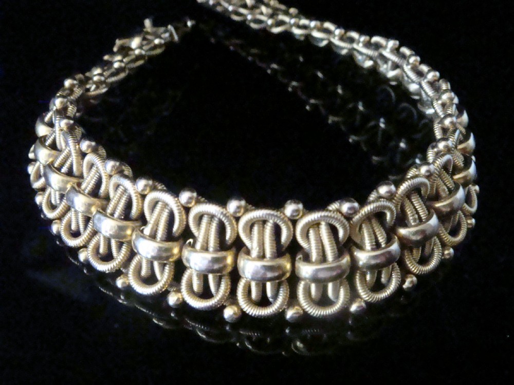 An Edwardian 18ct yellow gold bracelet featuring intricate interlocking wirework links and granulated bead detailing. View VI