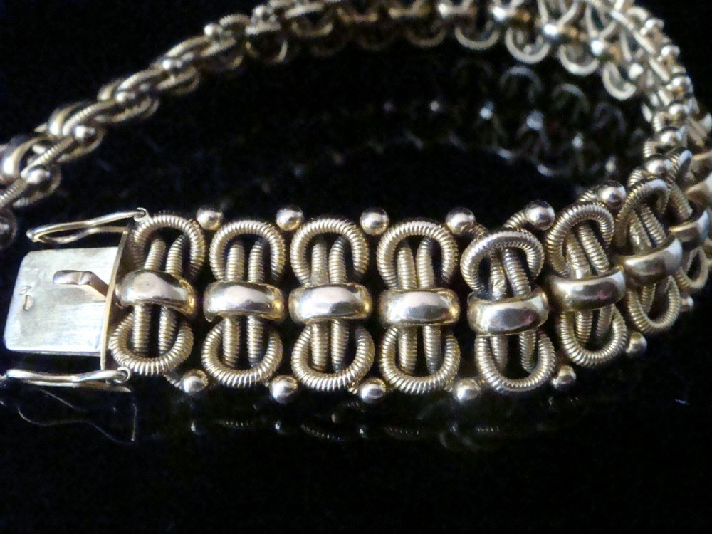 An Edwardian 18ct yellow gold bracelet featuring intricate interlocking wirework links and granulated bead detailing. View VII
