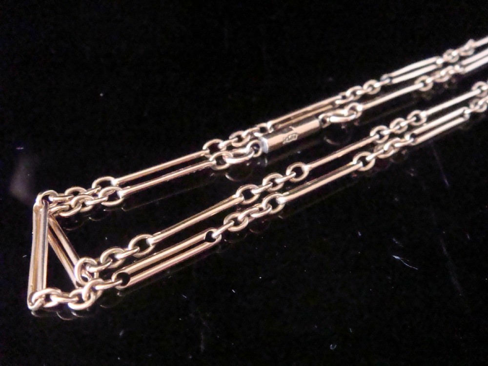 An Edwardian 9ct gold trombone link chain featuring elongated cylindrical links connected by circular jump rings.
