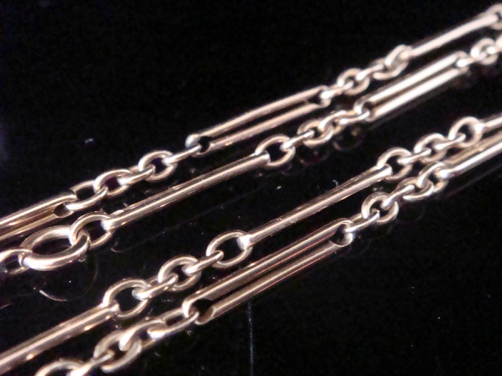 An Edwardian 9ct gold trombone link chain featuring elongated cylindrical links connected by circular jump rings. View V