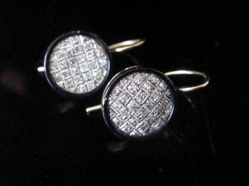 Pair of circular Edwardian drop earrings featuring pave-set diamonds surrounded by a black enamel border with wire fittings.