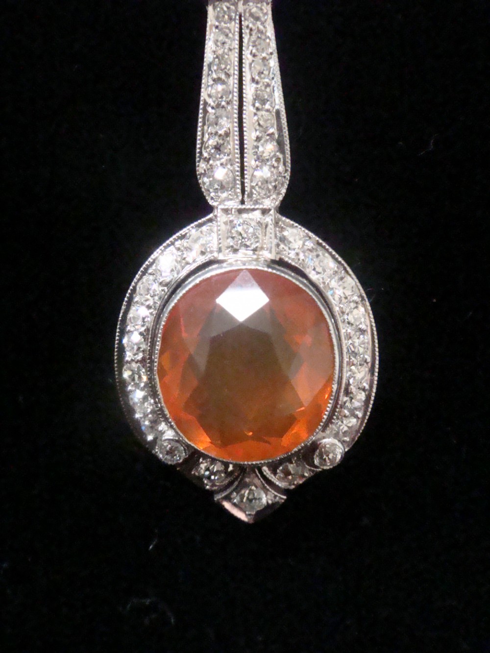 An Edwardian 18ct white gold pendant necklace featuring two oval cut orange fire opals framed by small diamonds along an articulated geometric drop. View II