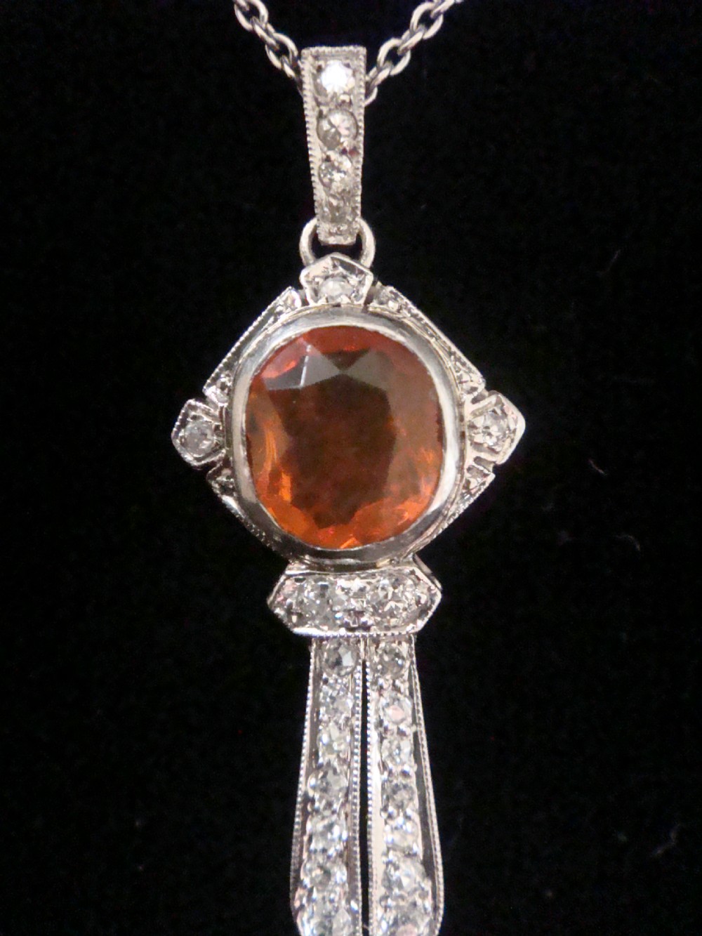 An Edwardian 18ct white gold pendant necklace featuring two oval cut orange fire opals framed by small diamonds along an articulated geometric drop. View IV