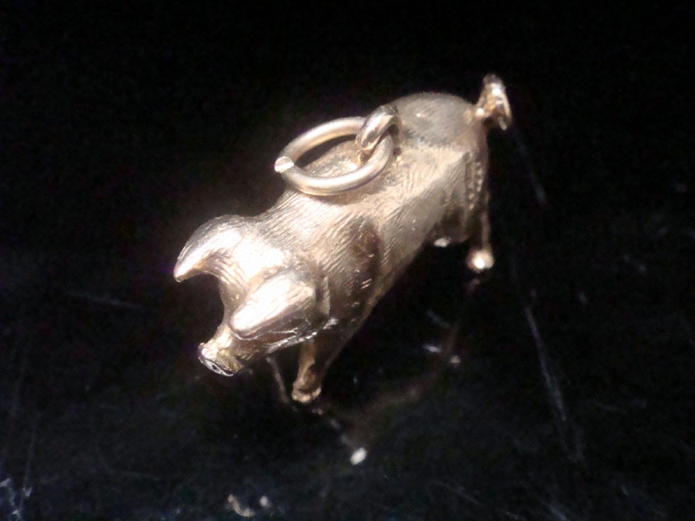 A small three-dimensional yellow gold pig pendant featuring a textured body, curled tail, and attached suspension loop. View II