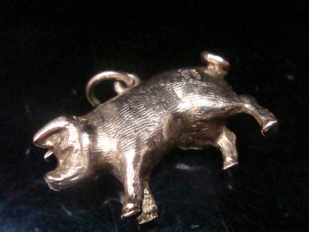 A small three-dimensional yellow gold pig pendant featuring a textured body, curled tail, and attached suspension loop. View III
