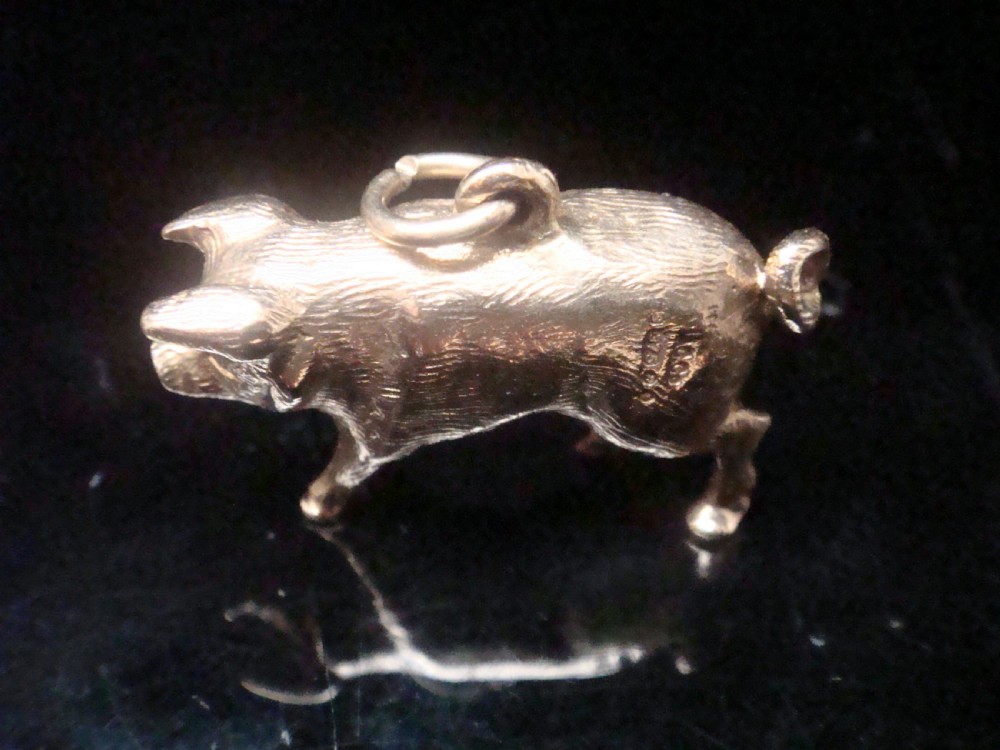 A small three-dimensional yellow gold pig pendant featuring a textured body, curled tail, and attached suspension loop. View IV