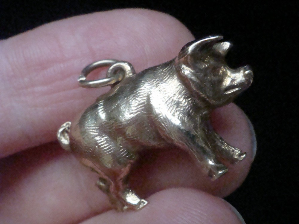 A small three-dimensional yellow gold pig pendant featuring a textured body, curled tail, and attached suspension loop. View V