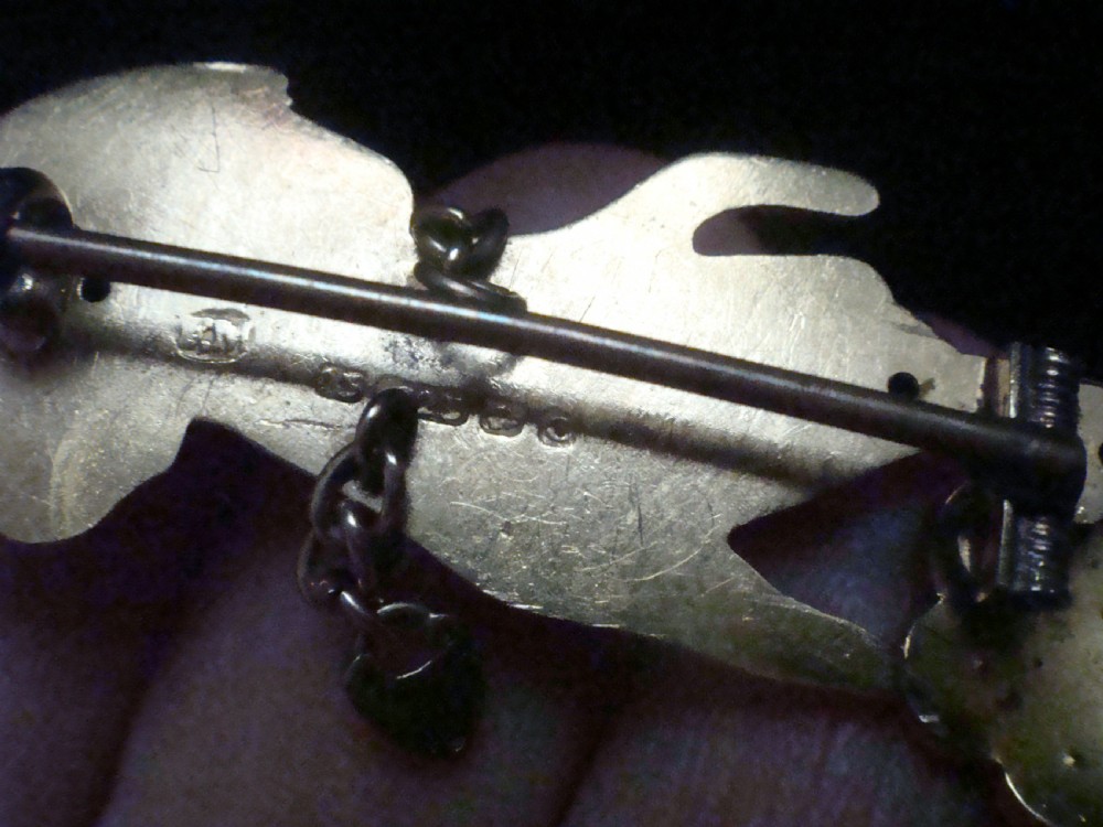 A Victorian 15ct yellow gold brooch carved in the shape of a hand with a lace cuff holding a seed pearl flower with a small heart padlock charm attached. View III
