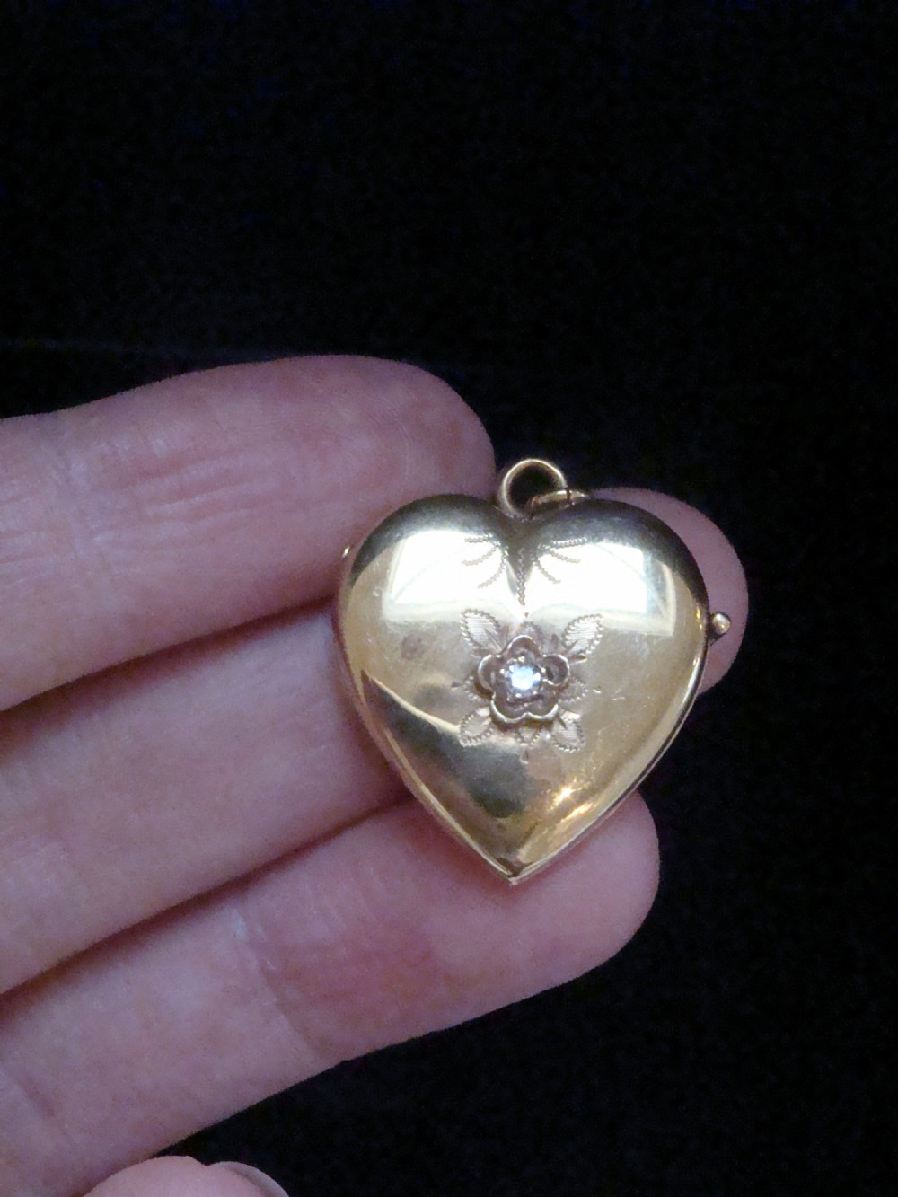 An antique gold heart-shaped locket featuring floral hand engraving and a central flush-set diamond. View III