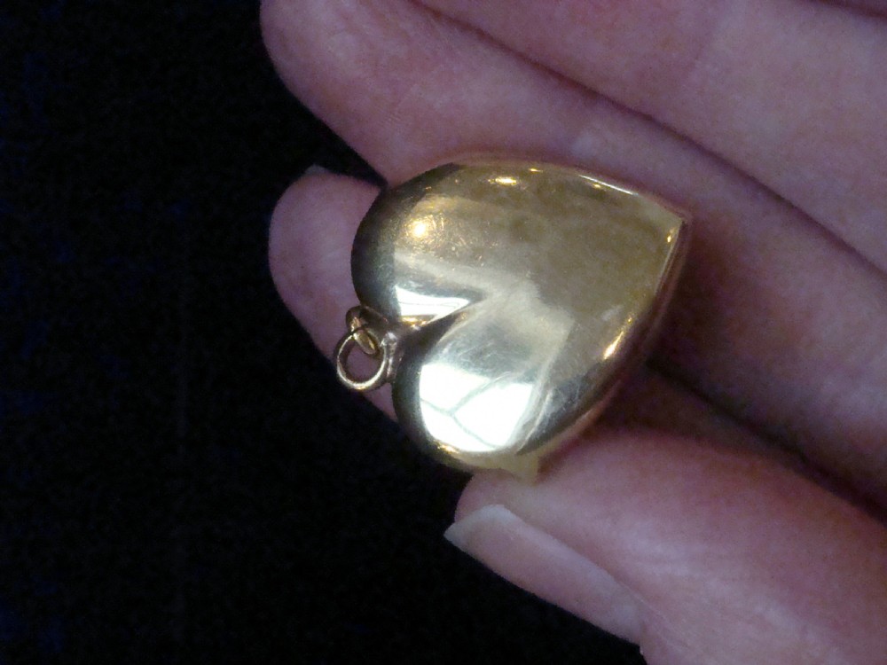 An antique gold heart-shaped locket featuring floral hand engraving and a central flush-set diamond. View IV