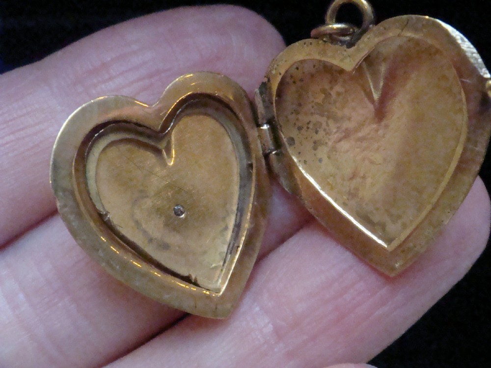 An antique gold heart-shaped locket featuring floral hand engraving and a central flush-set diamond. View V