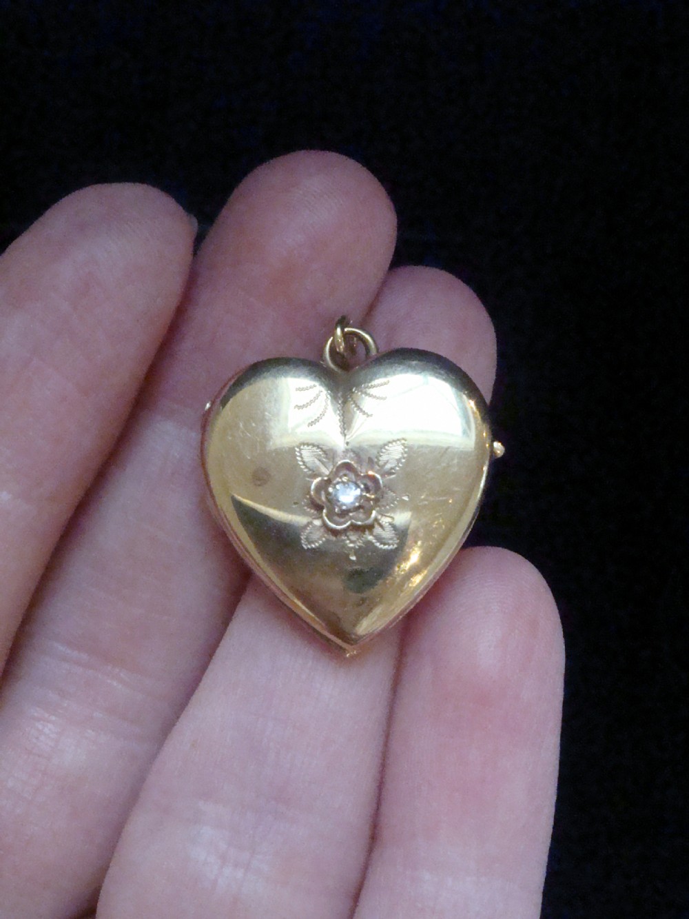 An antique gold heart-shaped locket featuring floral hand engraving and a central flush-set diamond. View VI