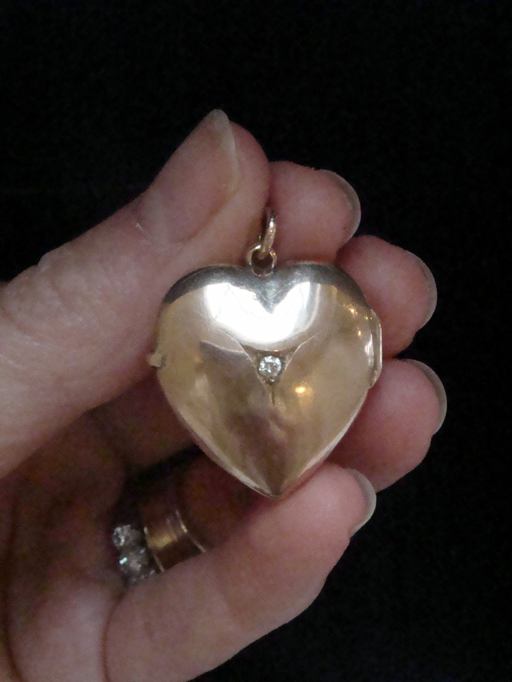An Edwardian 9ct gold puffed heart locket featuring a centrally inset old cut diamond within a starburst setting.